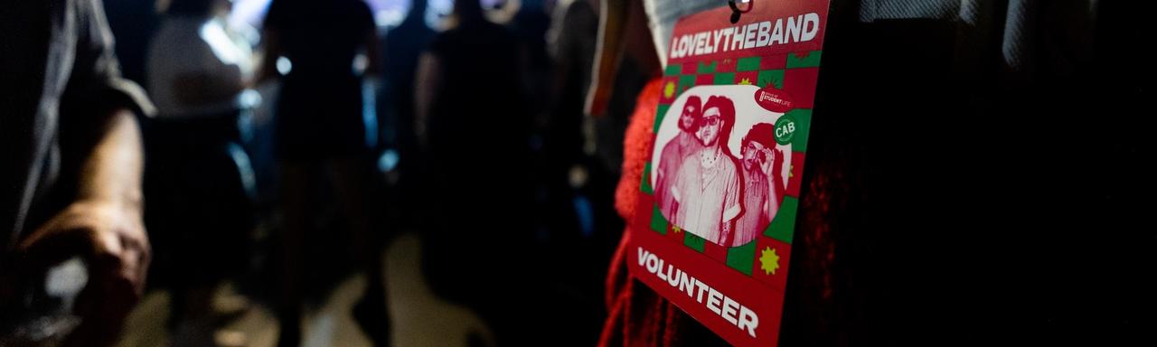 A person wearing a badge that reads "Lovely the Band Volunteer"